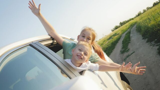 Happy family travel by car. Children getting ready for road trip on a sunny day. Two kids in car near the open window. Summer vacation concept.