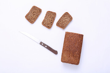 Sliced whole grain rye bread with knife on white background