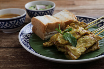 Local Thai food pork satay with oeanut dipping sauce isolated in wood background