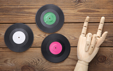 Wooden hand shows rock gesture and vinyl record on wooden background