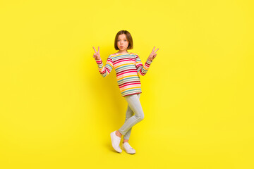 Fototapeta na wymiar Full size photo of charming nice happy small girl send air kiss make v-signs isolated on yellow color background