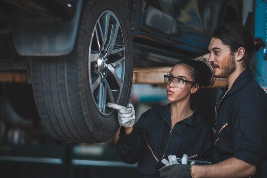 male and female machanic wearing uniform doing automoblie checklist with happy face, discussing on work with coorperation.