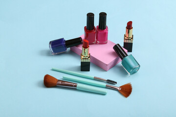 Minimalistic beauty scene or showcase with bottles of nail polish, makeup brush, lipstick and platforms on a blue background