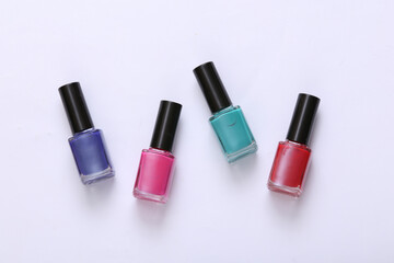 Obraz premium Bottles of colored nail polish on white background. Top view