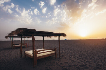 Sandy beach with sun beds at sunset