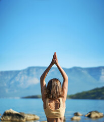 Back view woman practices yoga with hands up pose at nature with beutiful mountains view. Body and mental welness