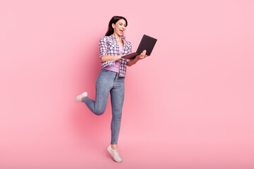 Full length body size view of attractive cheerful girl jumping using laptop isolated over pink pastel color background