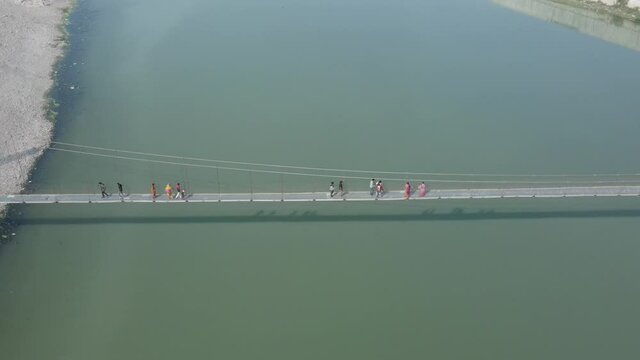 Drone flies high in the sky above floating clouds. Below, overlooks an impressive view of the Hanging bridge near machhu dam, Aerial. 4K