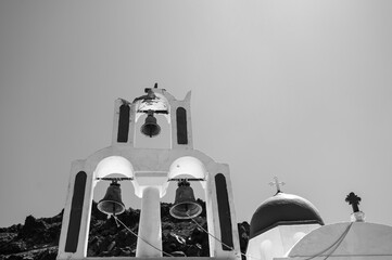 Fototapeta na wymiar Bell tower of the traditional Greek Orthodox church on the island of Santorini. Sky and rock on background. Bottom view. Black and white.