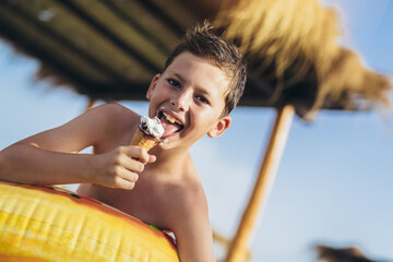 Young boy at the beach eating icecream on a summer day. © Mediteraneo