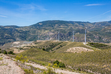 Fototapeta na wymiar Group of wind turbines in the mountains of Andalusia, Spain. They are built in a line. Blue sky, sunny day.
