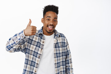 Yes, very good. Black guy smiling, showing thumb up in approval, like and agree. African american...