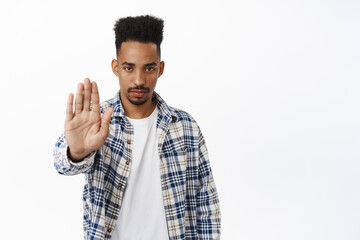 Stop. Serious and determined african american guy extend palm, saying no, rejecting and prohibit...