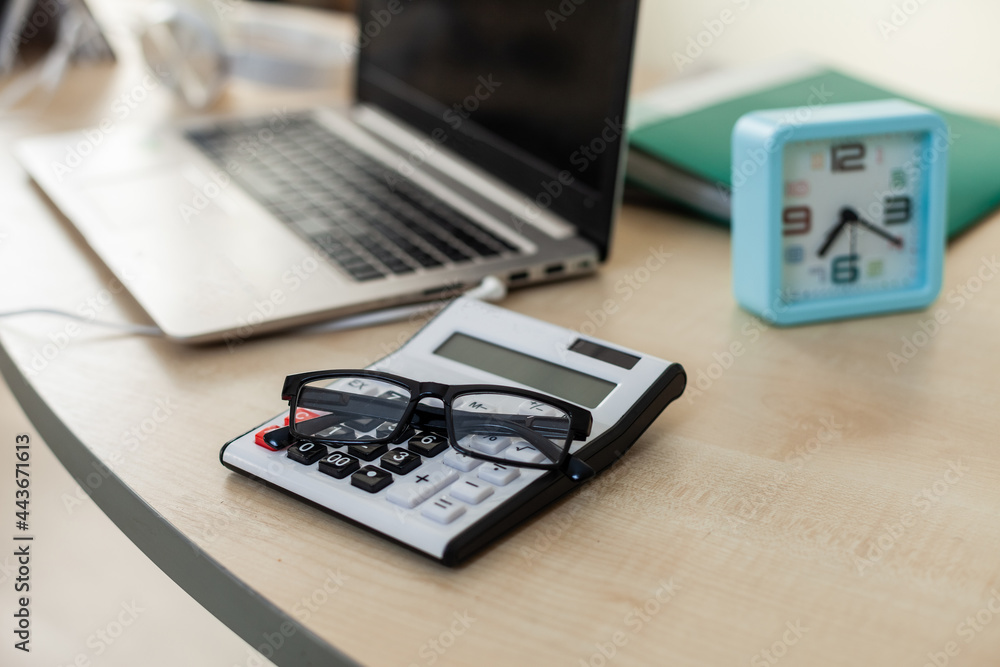 Poster calculator with glasses close up on table with workspace