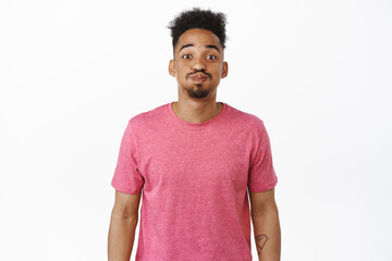 Funny african american man with afro hair and moustache, making silly pouting face and smiling,...