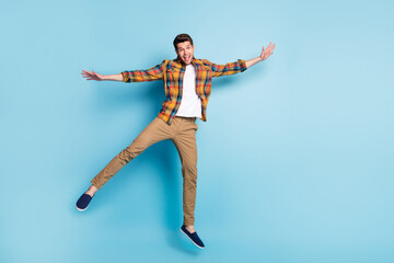 Fototapeta na wymiar Photo of attractive carefree young gentleman wear checkered shirt jumping high smiling isolated blue color background