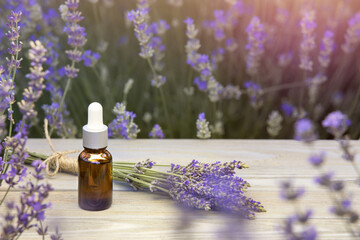 Essential lavender oil in the bottle with dropper on the gray wooden desk. Horizontal close-up.