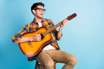 Photo of charming funny young gentleman wear checkered shirt singing playing guitar empty space...