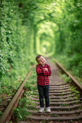 Naklejka na ściany i meble The boy walking in forest at summer day. A railway in the summer forest