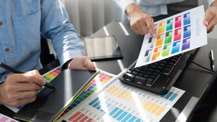 graphic designer team working on web design using color swatches editing artwork using tablet and a...