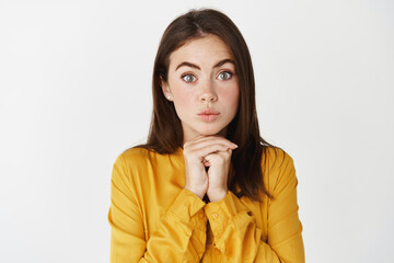 Close-up of intrigued and excited silly woman looking at camera with interest, staring at you as...