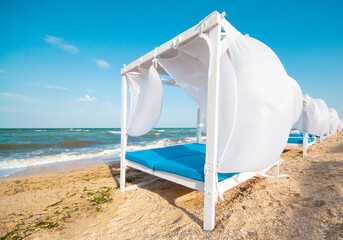 Wooden canopies with white curtains for luxury summer relaxation by the sea.