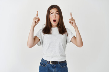 Shopping concept. Impressed young woman staring at promo with awe, pointing fingers and looking up...