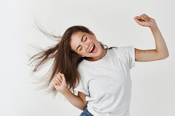 Haircare and beauty concept. Happy young woman dancing and whip healthy shiny hair, having fun,...