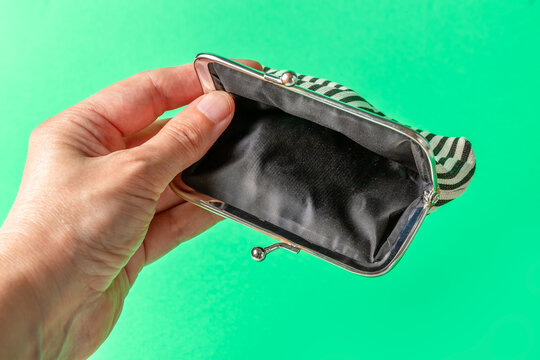 Open Empty Wallet In Hand On A Green Background. Poverty Concept. Below The Poverty Line.