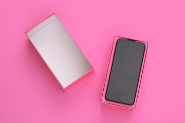 New modern smartphone in a packing box on pink background. Top view. Minimalism.