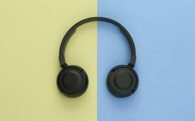 Black stereo headphones on colored pastel background. Top view