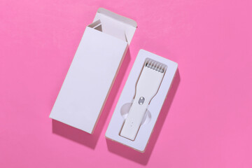 Fototapeta premium New Wireless Hair Clipper in box on pink bright background. Top view