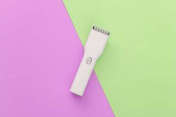 Wireless hair clipper on pink green background. Top view