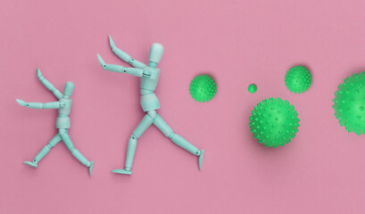 Puppets runs away from the molecules of the virus strain on pink background. Covid 19 pandemic