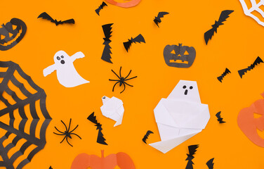 Handmade paper cut Halloween decor on orange background. Halloween background. Top view. Flat lay