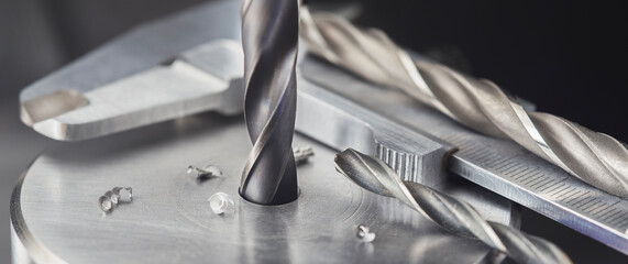 drill bit make holes in steel billet on industrial drilling machine with ruler and caliper. Metal work industry. multi cutting tool and end mill.