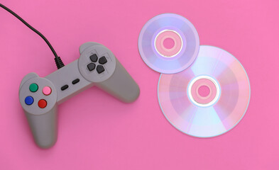 Retro gamepad and CD's on pink background. Gaming, video game competition. Top view