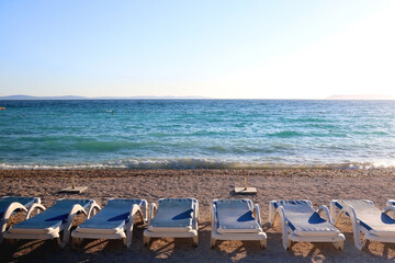 Deck chairs arranged on a beautiful beach near Split, Croatia. Selective focus.