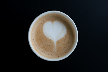 Above of Cappuccino. Take-out coffee in cardboard thermo cup on black surface. top view
