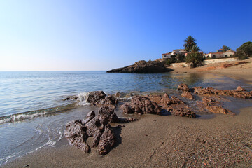 Fototapeta na wymiar Orilla del mar, con rocas, arena y casas junto al mar. Playa de Bolnuevo, Mar Mediterráneo, en Mazarrón (Murcia-España).