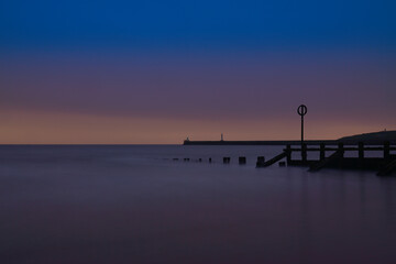 Naklejka na ściany i meble Long Exposure of Aberdeen Beach with lighthouse and breakwater pier. located in Aberdeenshire, Scotland.