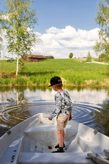 A child in a boat. The child throws stones into the lake. Splash. Walk to nature. Vacation at home. Children's pranks.