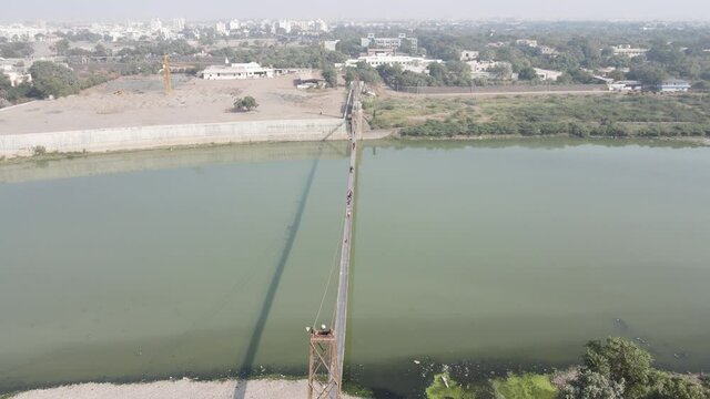 Drone flies high in the sky above floating clouds. Below, overlooks an impressive view of the Hanging bridge near machhu dam, Aerial. 4K