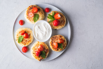 Cottage cheese pancakes with strawberries, mint and sour cream on a light background. syrniki. healthy dessert