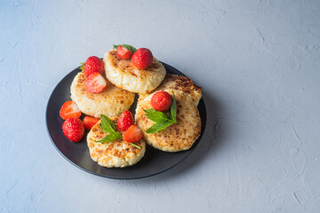 Cottage cheese pancakes with strawberries, mint and sour cream on a light background. syrniki. healthy dessert