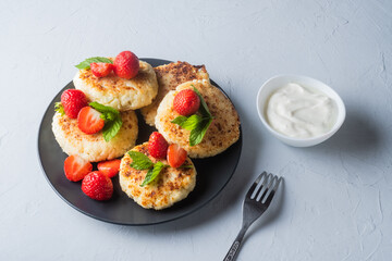 Cottage cheese pancakes with strawberries, mint and sour cream on a light background. syrniki. healthy dessert