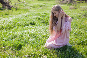 Beautiful blonde woman collects flowers in flowering garden in spring