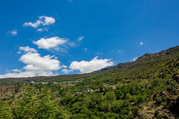 Andalusia, Spain, Village of Pampaneira could be seen on the green mountain slope. Spring sunny day travel photograph.