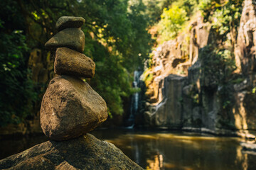 Rock balancing example in front of waterfull immersed in pristine nature. Concept of meditation and balance, zen connection with nature