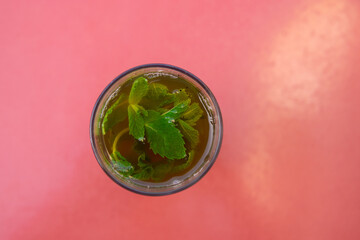 Top view of a Glass of moroccan tea with mint plant with copy space in red background